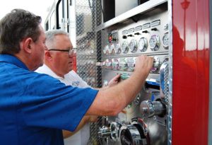 E-ONE sales representative Virgil Slagle (blue shirt) shows Chief Chapman details of the new fire truck.
