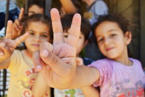 Syrian refugee children at a half-built apartment block near Reyfoun in Lebanon, close to the border with Syria, give the peace sign. The families fled Syria due to the war and are now living on a building site. (Photo: Eoghan Rice)