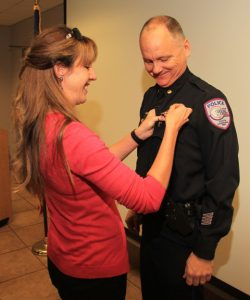 Lisa Grainger pins a new badge on John Grainger at Monday’s ceremony. The couple has one son, 12-year-old Alex.