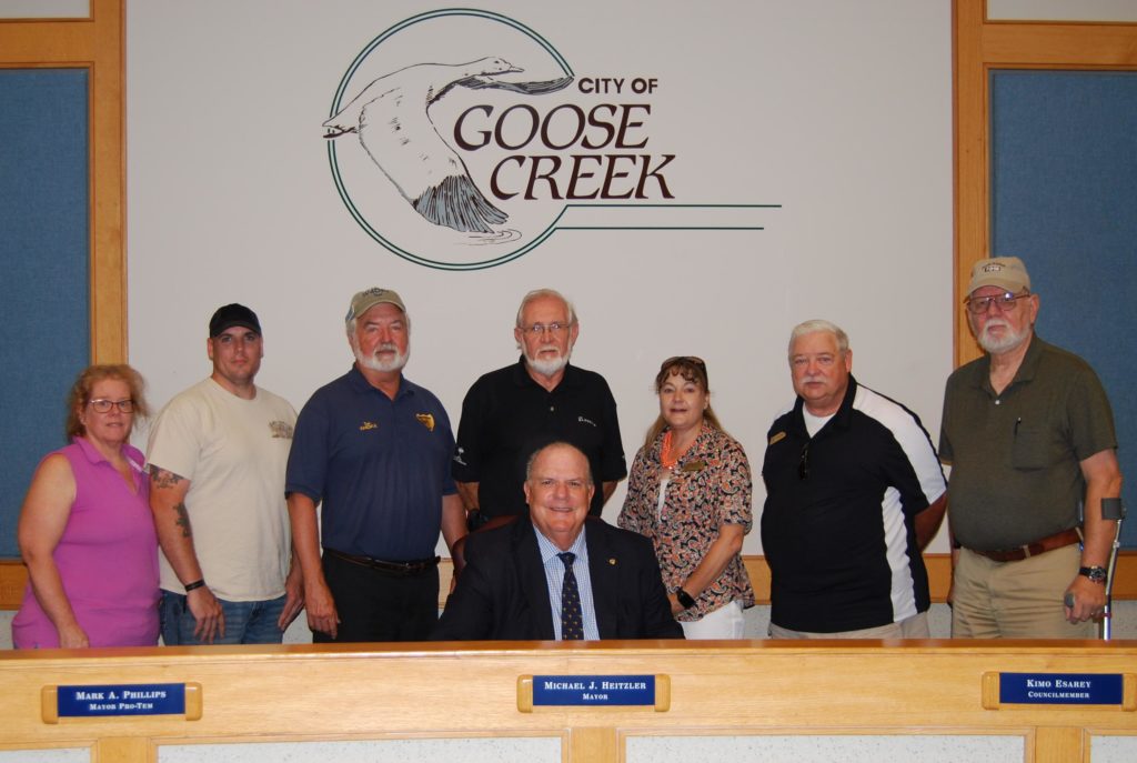 Pictured: Goose Creek Mayor Michael Heitzler (seated) is pictured at the June 13 proclamation signing with Amateur Radio operators (l-r) Peggy Reese (Amateur Radio call sign W4ZBR), Jay Clark (W4MGR), Tom Lufkin (W4DAX), Steve Lamendola (KE4THX), Beverly Boyd (W3BRB), David Merritts (AE4ZR) and Ken Curtis (KM4TKL)